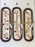 Three long oval wooden trays labeled A, B, and C, each containing a pressed floral arrangement in white resin with pink and red petals, tied with twine and a small paper tag, on a white background.