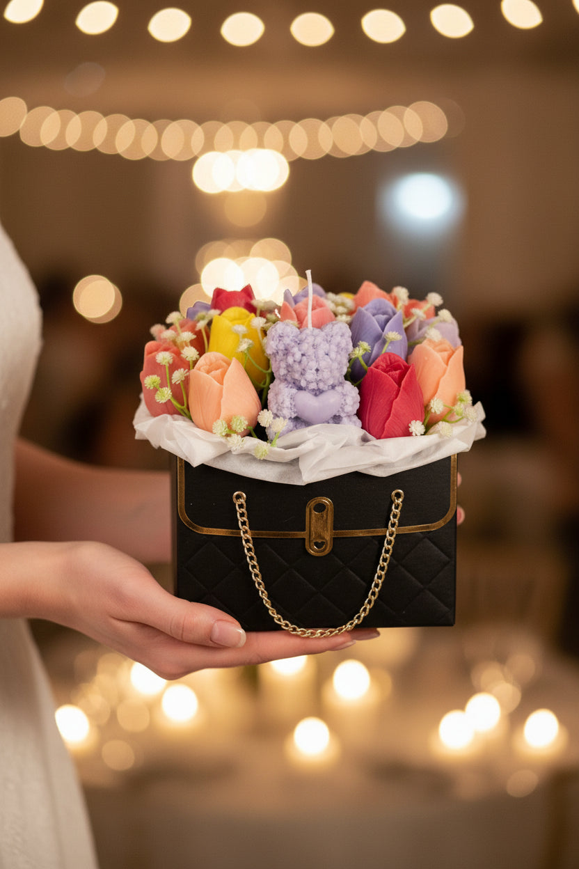 Colorful flower arrangement with a teddy bear inside a black handbag on a white background