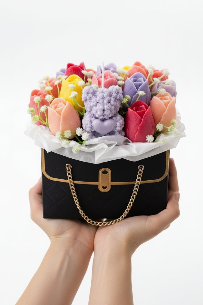 Colorful flower arrangement with a teddy bear inside a black handbag on a white background