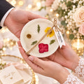 A tray of pressed flower keepsake candles, every design different — a Wické gift card lets them choose their own