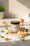 A Wické Artisan Jasmine No. 46 scented candle in a frosted peach-colored glass jar with a black lid and a white label, displayed on a white surface.