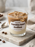 Wicke Vanilla Iced Coffee candle in a glass container on a marble surface with coffee beans and a spoon.