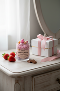 A WICKÉ Strawberry Biscuits aroma candle in a clear glass jar, filled with pink wax and topped with miniature pink and beige biscuits, on a white background.